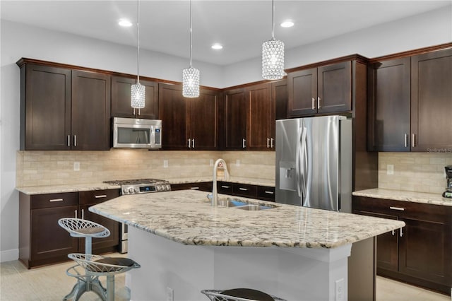 kitchen featuring a kitchen breakfast bar, sink, decorative light fixtures, appliances with stainless steel finishes, and dark brown cabinets