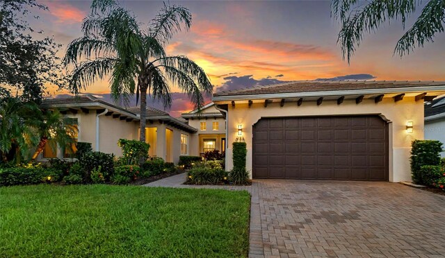 view of front of property featuring a front lawn, decorative driveway, an attached garage, and stucco siding