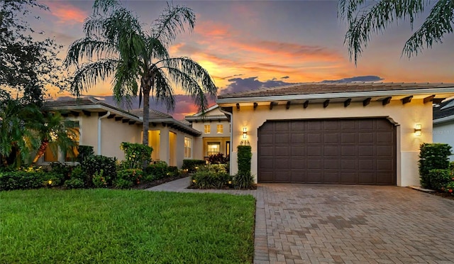 view of front facade featuring a garage, decorative driveway, a front lawn, and stucco siding