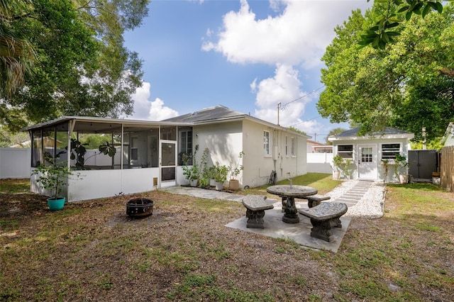 rear view of house featuring a patio, a sunroom, and a fire pit