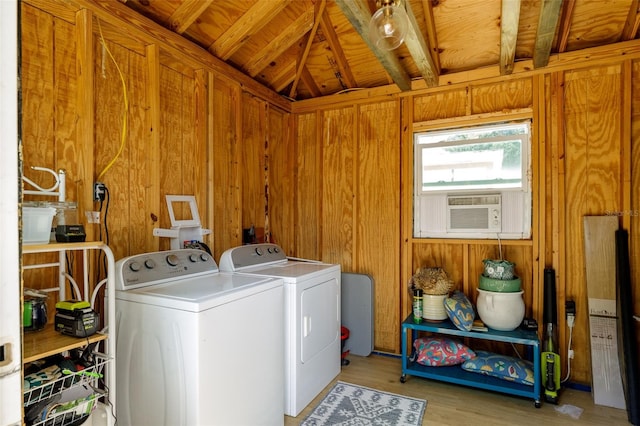 laundry room with washing machine and clothes dryer, light wood-type flooring, wood walls, and wood ceiling