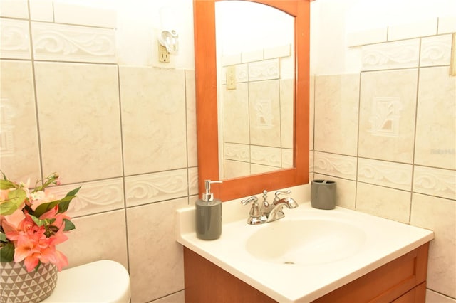 bathroom featuring vanity, tile walls, and toilet