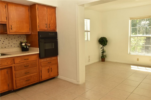 kitchen with light tile patterned floors, oven, plenty of natural light, and tasteful backsplash