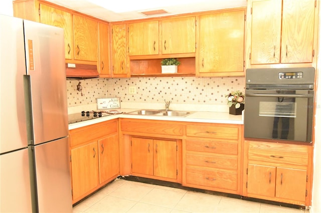 kitchen with white gas cooktop, sink, custom range hood, black oven, and stainless steel fridge