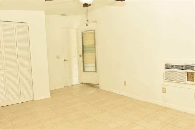 interior space with light tile patterned flooring, ceiling fan, and a wall unit AC