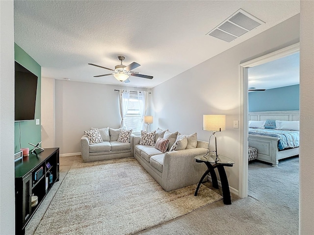 carpeted living room with ceiling fan and a textured ceiling