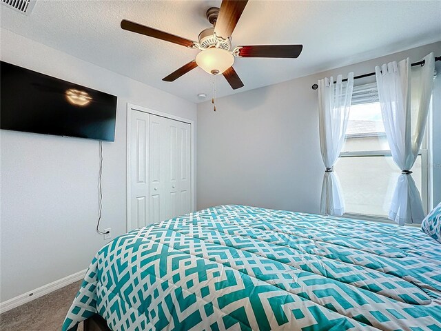 carpeted bedroom featuring a closet, ceiling fan, and a textured ceiling