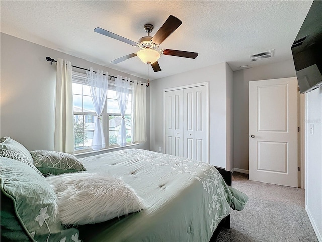 bedroom with a textured ceiling, carpet floors, a closet, and ceiling fan