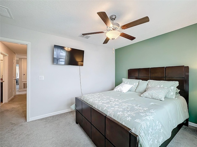 carpeted bedroom featuring ceiling fan and a textured ceiling