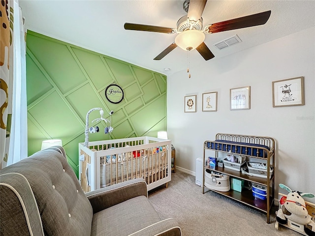 carpeted bedroom featuring a crib and ceiling fan