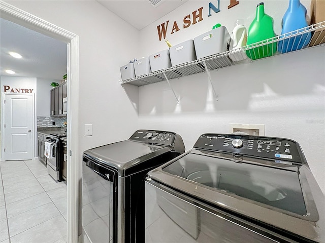 clothes washing area with washing machine and clothes dryer and light tile patterned floors