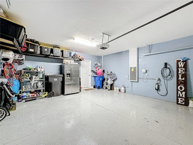 garage with a garage door opener, electric panel, and stainless steel fridge