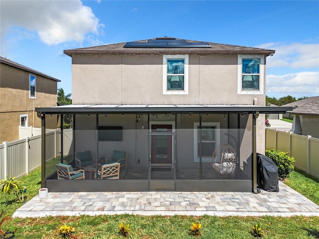 rear view of house featuring a patio, a sunroom, and solar panels