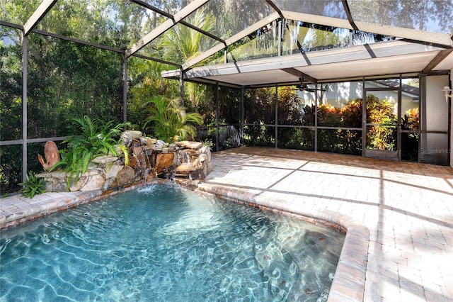 view of pool featuring glass enclosure, pool water feature, and a patio area