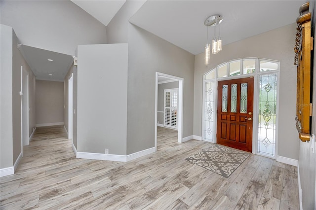 entryway featuring light hardwood / wood-style floors, vaulted ceiling, and an inviting chandelier