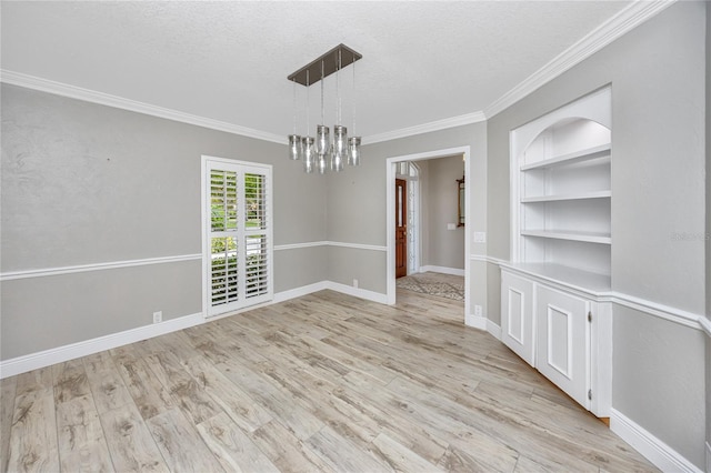 spare room featuring a notable chandelier, light wood-type flooring, crown molding, and a textured ceiling