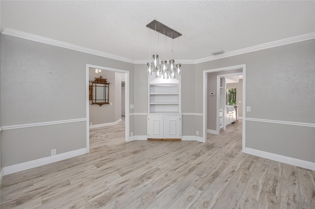 unfurnished dining area featuring ornamental molding, light hardwood / wood-style floors, an inviting chandelier, and a textured ceiling