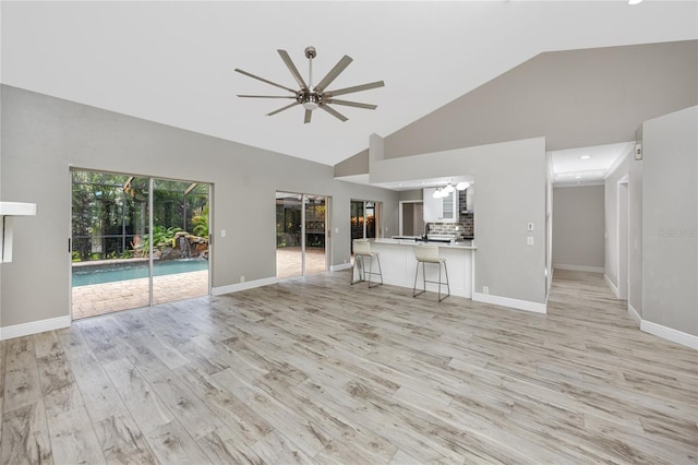 unfurnished living room featuring high vaulted ceiling, light hardwood / wood-style floors, and ceiling fan