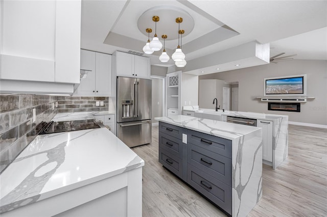 kitchen with light stone counters, pendant lighting, white cabinetry, light wood-type flooring, and high end refrigerator