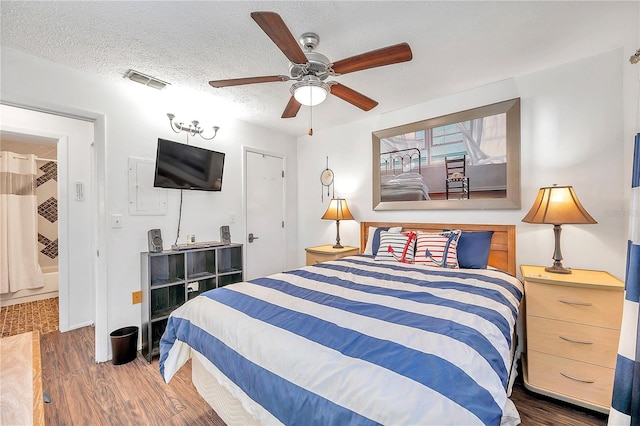 bedroom with ceiling fan, a textured ceiling, and dark wood-type flooring