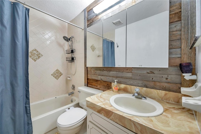 full bathroom featuring a textured ceiling, shower / tub combo, vanity, and toilet