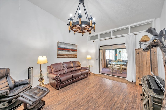 living room with a notable chandelier, a textured ceiling, hardwood / wood-style floors, and high vaulted ceiling