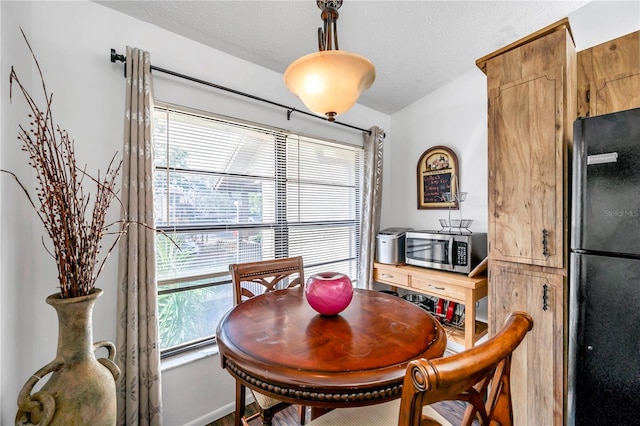 dining room featuring a textured ceiling, vaulted ceiling, and plenty of natural light