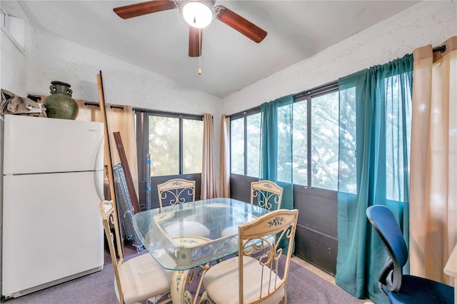 carpeted dining area with ceiling fan and vaulted ceiling