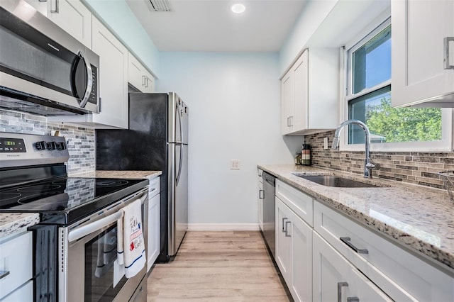 kitchen with appliances with stainless steel finishes, light wood-type flooring, sink, and white cabinets