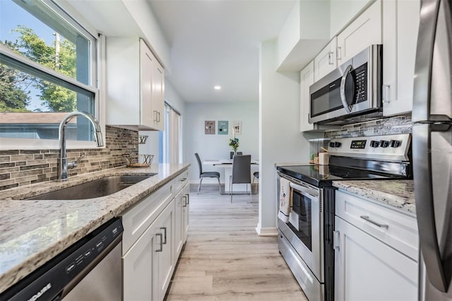 kitchen with light stone countertops, white cabinetry, sink, and stainless steel appliances