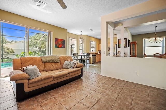 living room featuring a textured ceiling, ceiling fan with notable chandelier, and light tile patterned floors