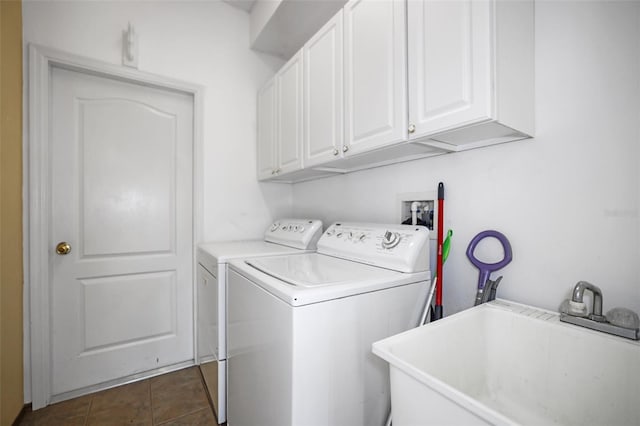 washroom featuring cabinets, dark tile patterned floors, washing machine and dryer, and sink