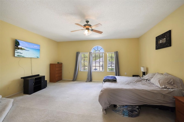 bedroom featuring ceiling fan, light colored carpet, and a textured ceiling