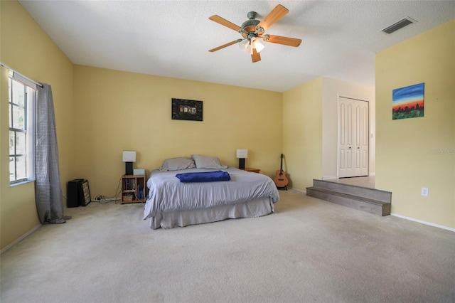 carpeted bedroom with ceiling fan, a textured ceiling, and a closet