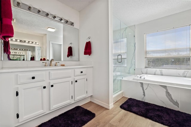 bathroom with vanity, wood-type flooring, shower with separate bathtub, and a textured ceiling