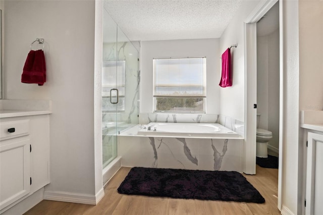 full bathroom featuring a textured ceiling, hardwood / wood-style floors, separate shower and tub, vanity, and toilet