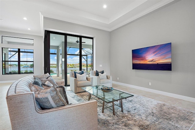 tiled living room with ceiling fan, a raised ceiling, and ornamental molding