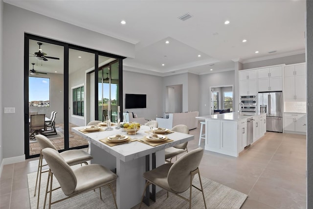 tiled dining space with ceiling fan and ornamental molding