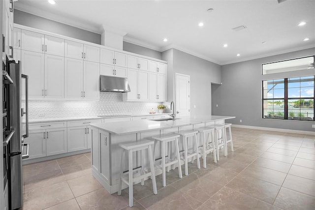 kitchen with a kitchen island with sink, a breakfast bar, and white cabinets