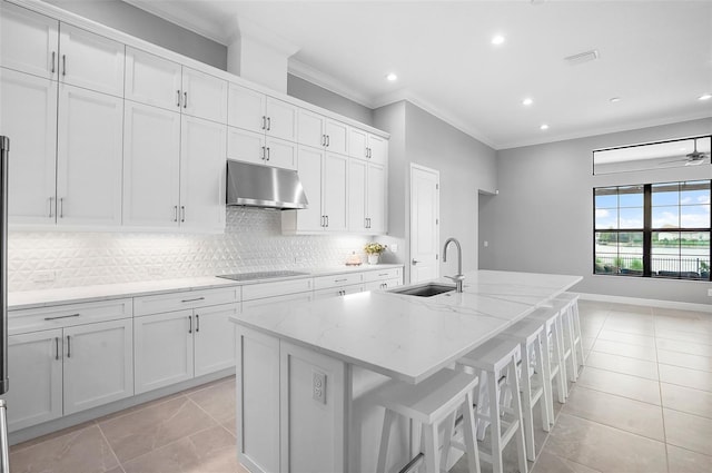 kitchen featuring sink, an island with sink, light tile patterned flooring, light stone counters, and white cabinetry