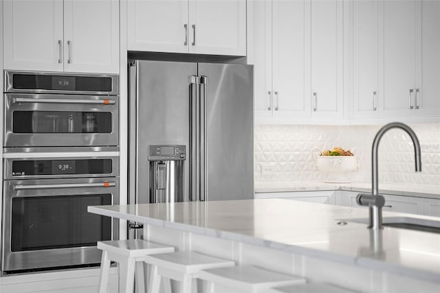 kitchen featuring white cabinetry, appliances with stainless steel finishes, and tasteful backsplash