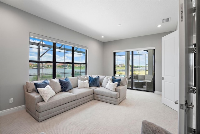 living room featuring a wealth of natural light, light carpet, french doors, and a water view