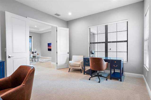 carpeted office with a tray ceiling and plenty of natural light