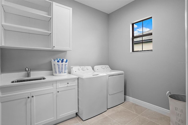 laundry area featuring washer and clothes dryer, sink, light tile patterned floors, and cabinets