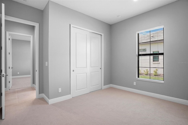 unfurnished bedroom with light colored carpet and a closet