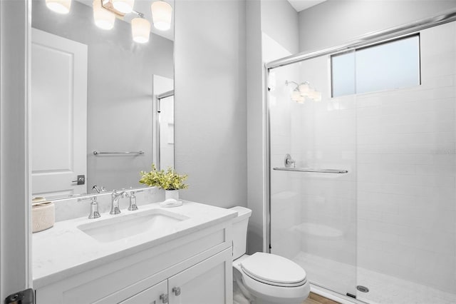 bathroom with a shower with door, vanity, and toilet