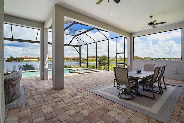 view of patio / terrace featuring a lanai, ceiling fan, a water view, and a pool with hot tub