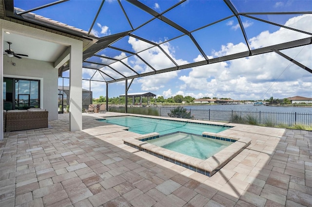 view of swimming pool with an in ground hot tub, a lanai, ceiling fan, a water view, and a patio