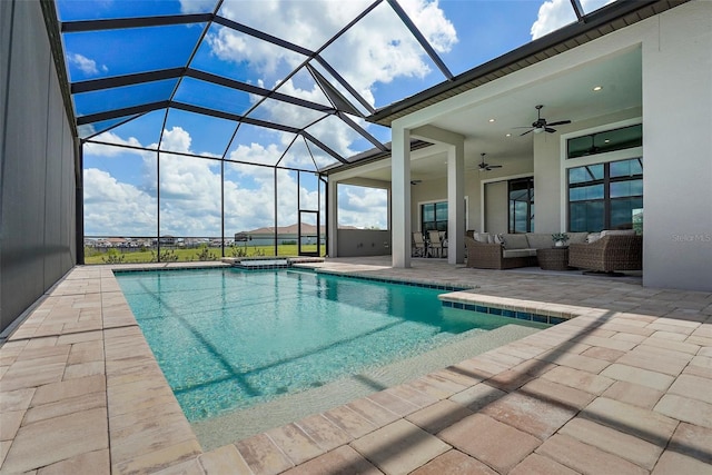 view of pool with outdoor lounge area, ceiling fan, a patio, and glass enclosure