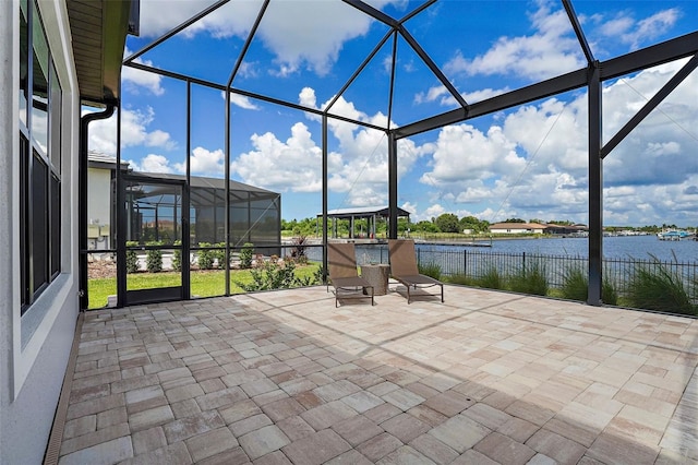 view of patio with glass enclosure and a water view